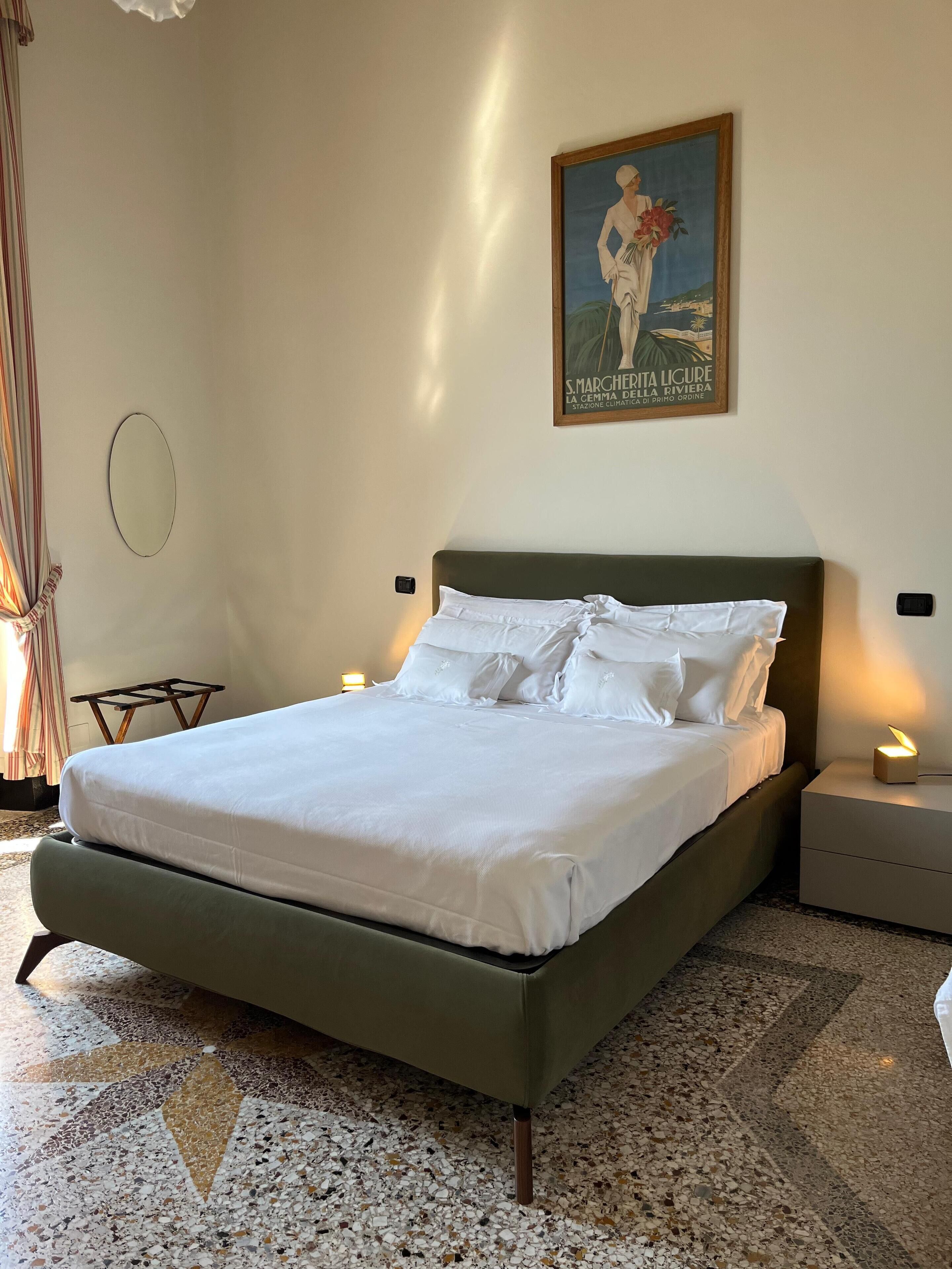 A neatly made bed with white linens and a green headboard in a hotel room.