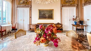 A luxurious room with a marble floor, a large chandelier, a sofa with a floral arrangement, and a painting on the wall.