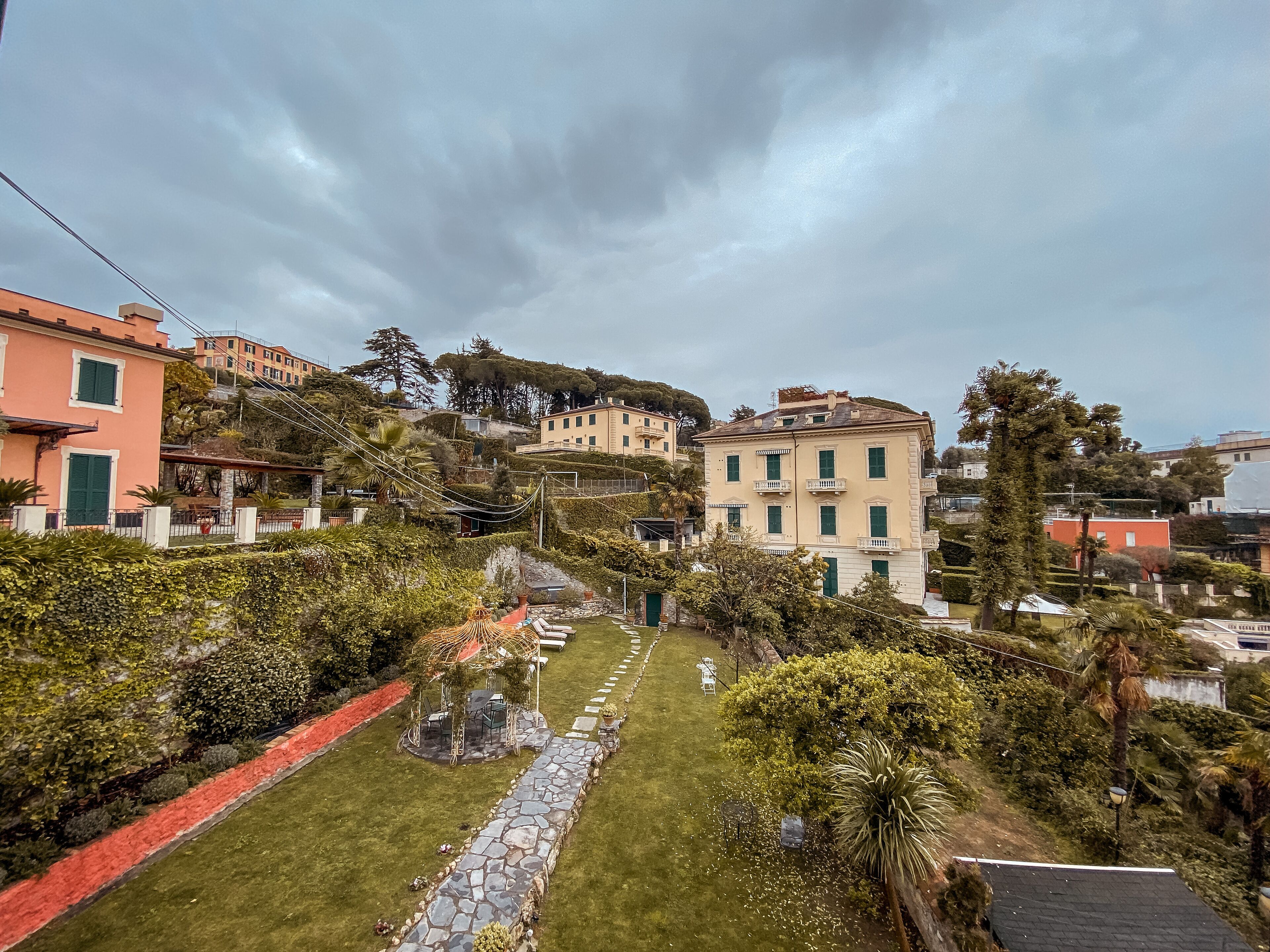 A residential area with a stone pathway, a gazebo, and buildings with balconies.