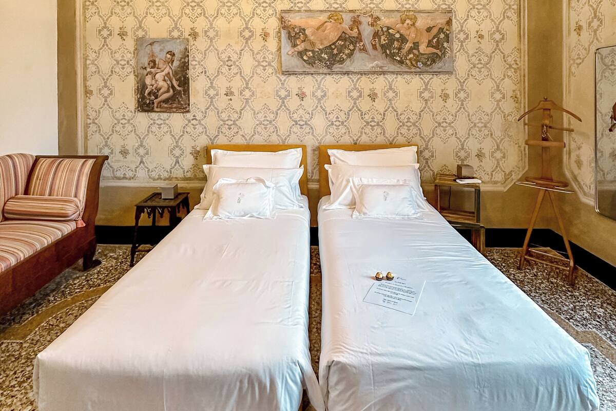 A room with two single beds, a sofa, a small table, and a decorative wall.