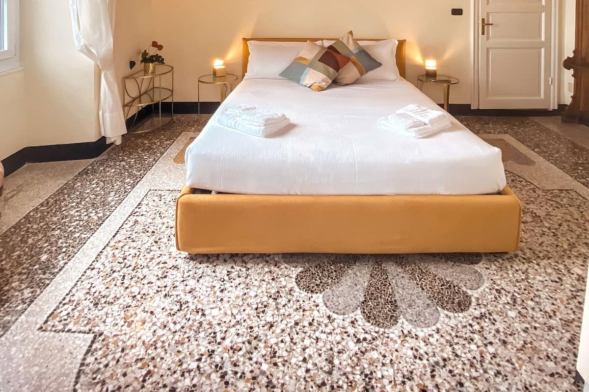 A hotel room with a large bed, a decorative ceiling, a painting, and a door.