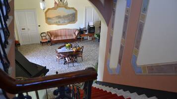 Un escalier menant à un espace repas comprenant une table et des chaises, un canapé et un téléviseur.