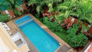 Una piscina rectangular envoltada de vegetació exuberant, amb una petita zona de solàrium i una zona coberta per seure.
