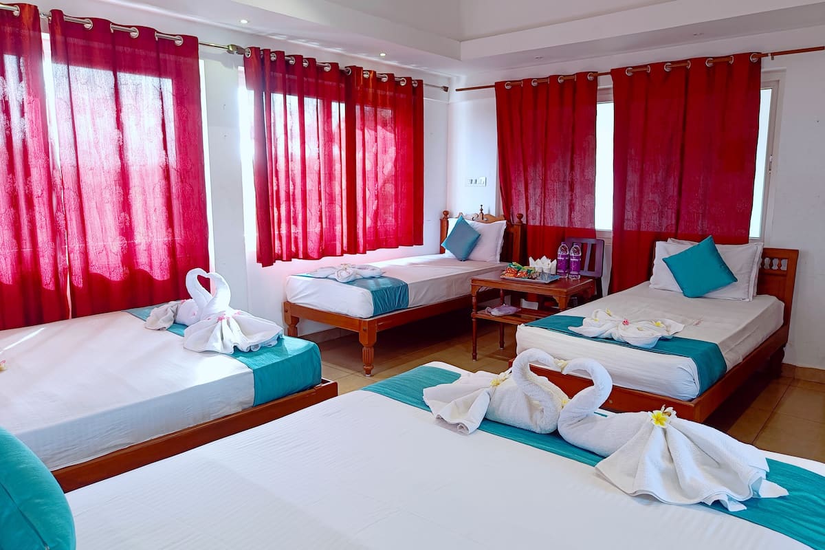 Une chambre d’hôtel avec deux lits, des rideaux rouges et une petite table avec des articles de toilette.