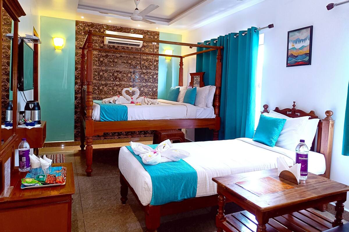 Une chambre d’hôtel avec deux lits, un lit à baldaquin en bois, un bureau avec une chaise, une table de chevet, un miroir, un climatiseur et un tableau au mur.