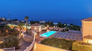 A swimming pool with a sunken area, surrounded by lounge chairs and a small gazebo, with a view of the sea and distant buildings. - Luxury villa with sea view, with Swimming pool (Campello)