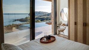 Ein Schlafzimmer mit einer großen Schiebetür zu einem Balkon mit Blick auf das Meer und die Hügel.