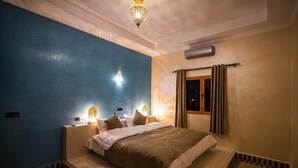 Une chambre à coucher avec un grand lit, un lustre et une fenêtre avec des rideaux.