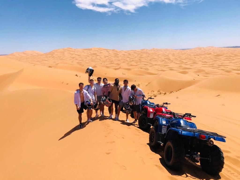 A group of people in a desert setting with ATVs.