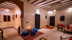 Un intérieur chaleureux avec un sol à motifs, un canapé, des poufs et une table décorative.