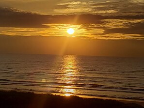 Ein Sonnenuntergang über ruhigem Meer, die Sonne spiegelt sich im Wasser.