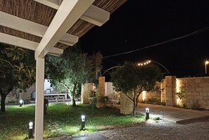 Relax under the stars in our serene garden patio, surrounded by lush trees and a beautifully lit pergola.