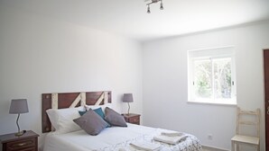 Una camera da letto con un letto, due comodini, una finestra e una sedia.