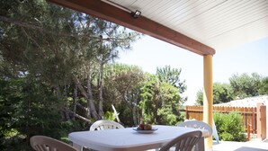 Una terrazza esterna con tavolo e sedie, circondata da alberi e un recinto in legno.