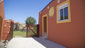 Un edificio con un cartello che recita 'Casa do Cedro', un vialetto sterrato e un cancello in legno.