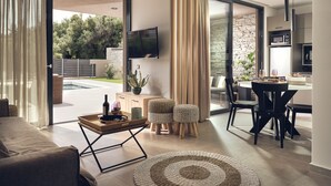 Ein modernes Wohnzimmer mit Sofa, Couchtisch, Fernseher und Essbereich mit Stühlen und Tisch.
