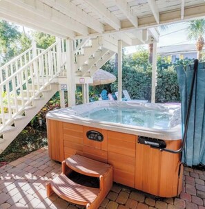 A wooden hot tub with a control panel, a wooden step, and a white staircase in the background.