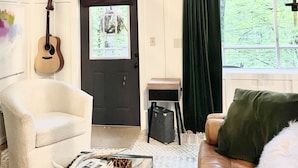 A cozy living room with a guitar, a deer skull, and artwork on the walls. - Live-in Art Gallery in Downtown Highlands / Walk to Main Street / Mountain Views (Highlands)
