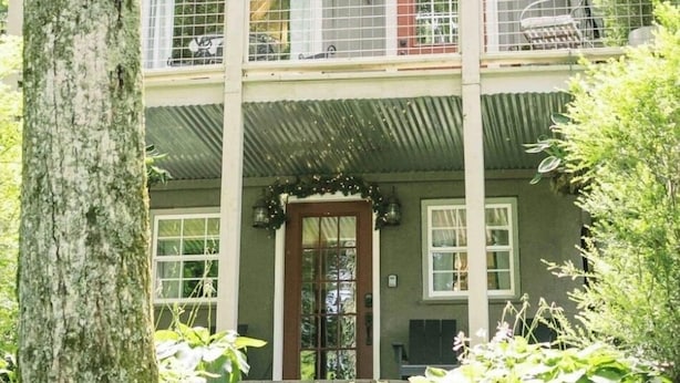 A two-story cabin with a balcony, surrounded by trees. - Live-in Art Gallery in Downtown Highlands / Walk to Main Street / Mountain Views (Highlands)
