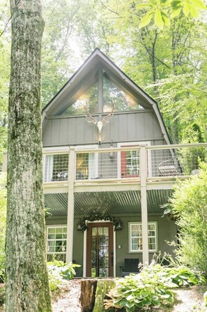 A two-story cabin with a balcony, surrounded by trees. - Live-in Art Gallery in Downtown Highlands / Walk to Main Street / Mountain Views (Highlands)