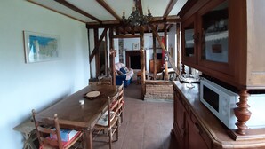 Cucina tradizionale con travi in legno, un tavolo da pranzo, sedie e un forno a microonde integrato.