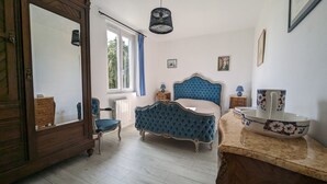 Camera da letto con un grande specchio, un letto imbottito blu, una cassettiera in legno e un piano d'appoggio in marmo.