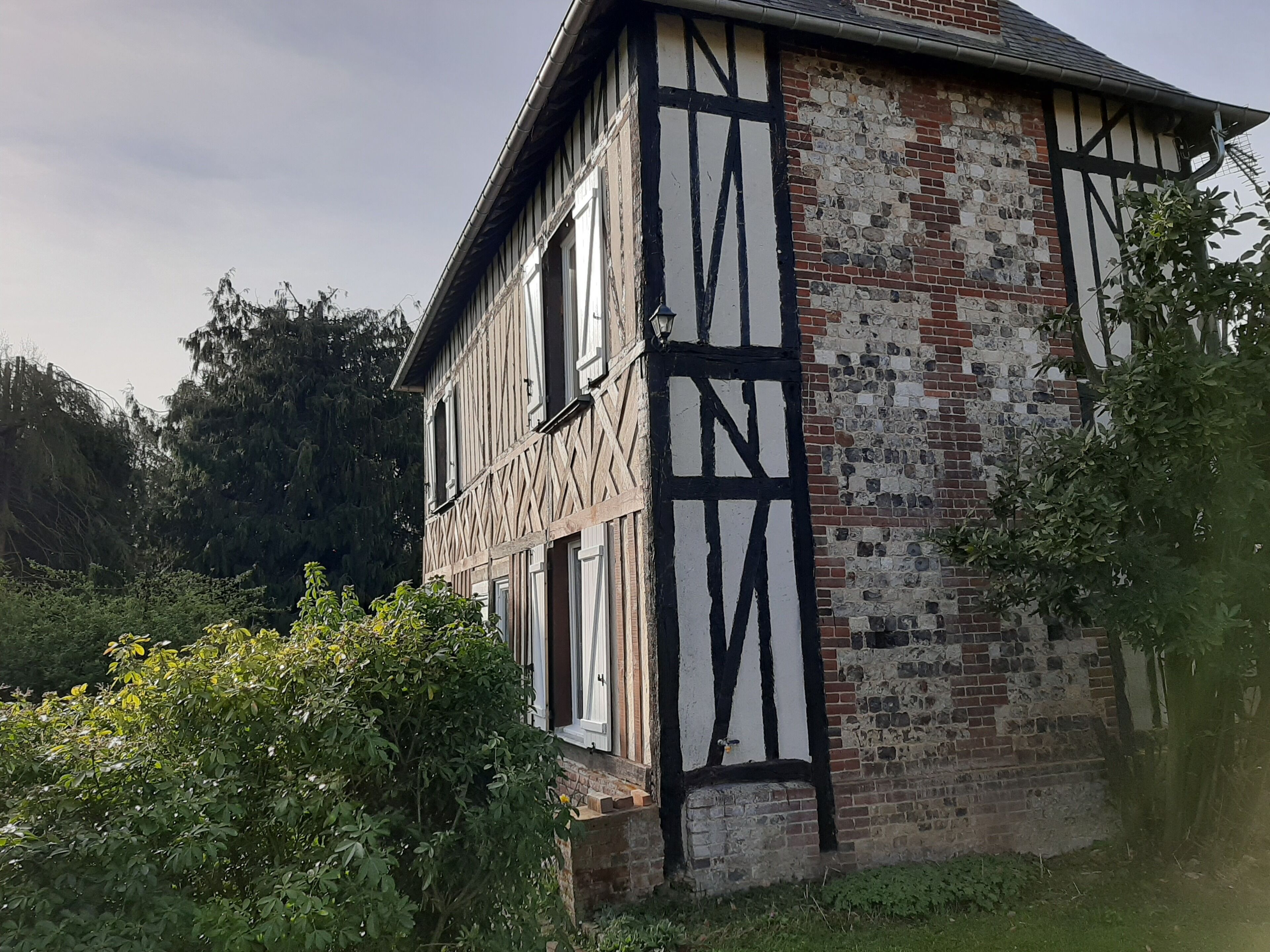 Une maison traditionnelle à colombages, avec une façade en briques et des éléments en bois peints en blanc.
