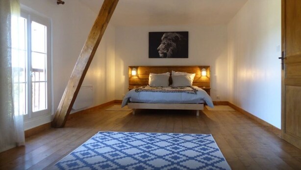 A bedroom with a sloped ceiling, a bed with a headboard, a patterned rug, and a framed picture on the wall.