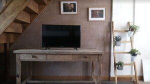 A rustic wooden desk with a flat-screen TV, a wooden staircase, and a wall-mounted plant shelf.