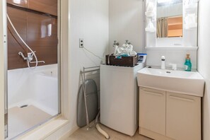 A compact bathroom with a shower, a sink, and a mirror.