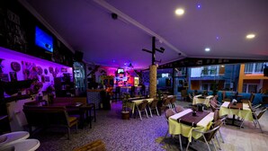 Un restaurant avec des tables et des chaises, un coin bar et un écran de télévision.