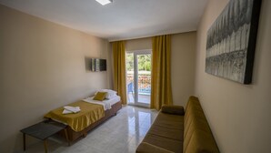 Une chambre d’hôtel avec un lit, un canapé, une petite table, une télévision et un tableau au mur.