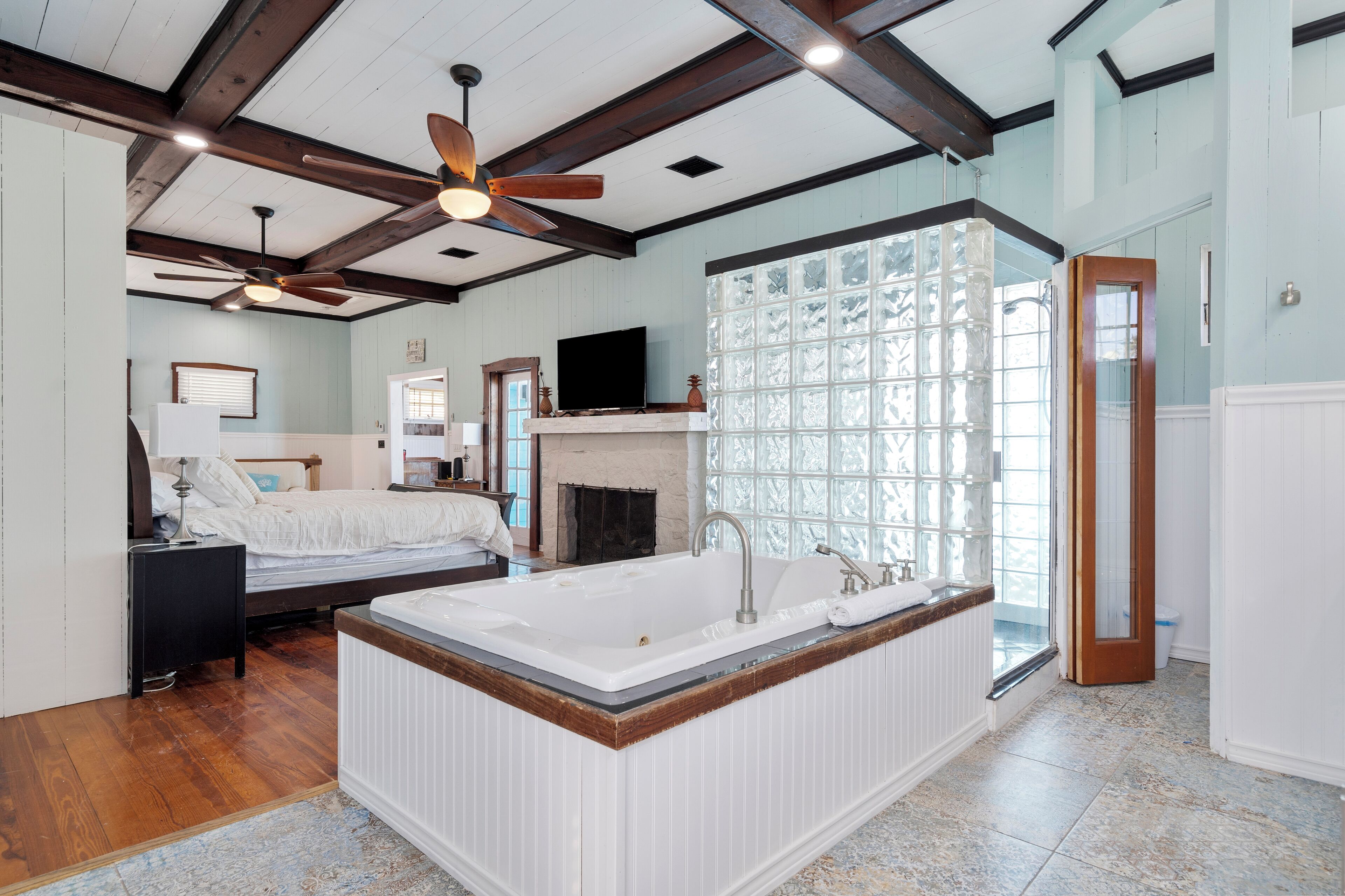 A spacious bedroom with a large bed, a built-in bathtub, and a fireplace.