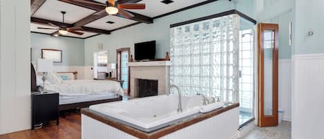 Une chambre spacieuse avec un grand lit, une baignoire intégrée et une cheminée.
