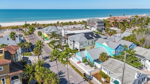 Zona residencial costera con casas, palmeras y una playa al fondo.