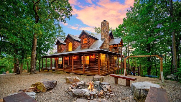 Un chalet rustique doté d’un foyer, de bancs en bois et d’une terrasse couverte.