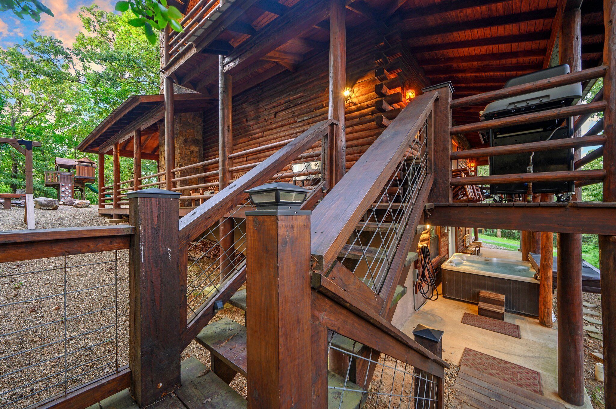 Een houten chalet met een hottub, houten trap en een omheind terras.