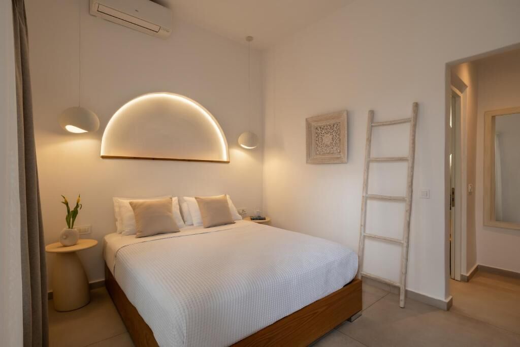 A bedroom with a bed, bedside lamps, a ladder, and a wall-mounted light fixture.