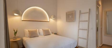 A bedroom with a bed, bedside lamps, a ladder, and a wall-mounted light fixture.