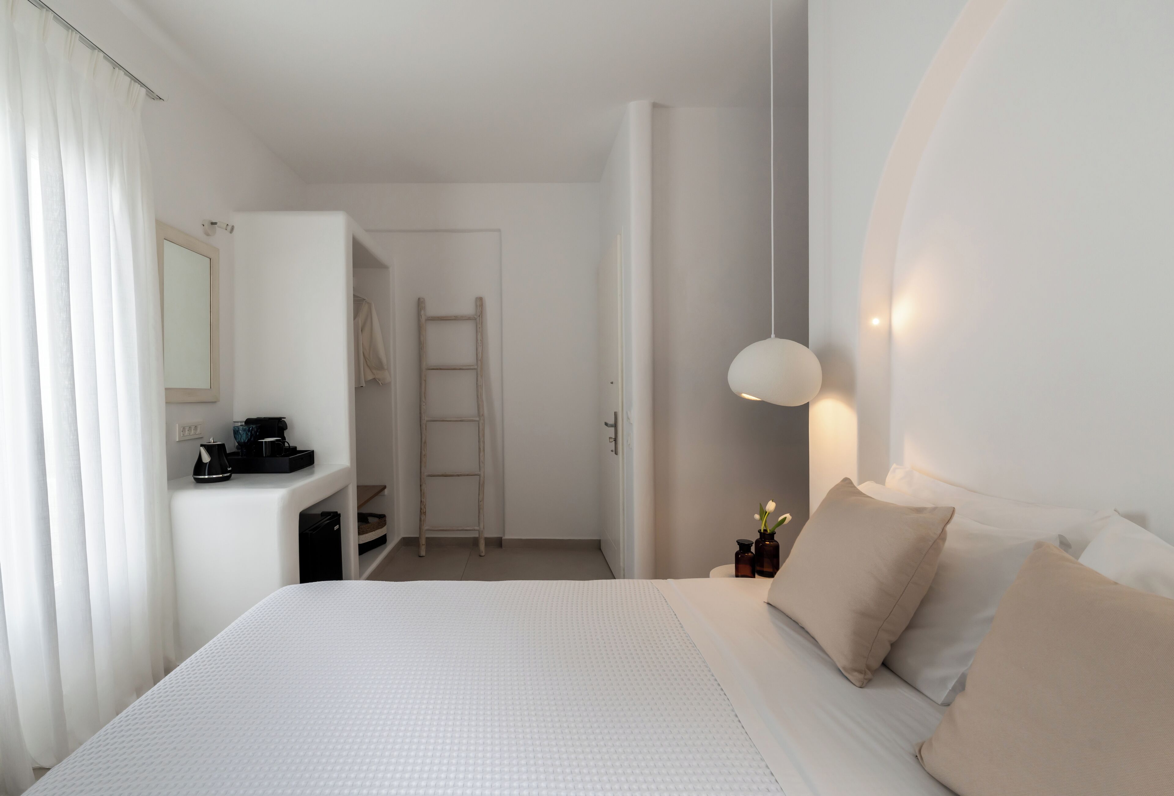 A hotel room with a bed, a desk, a lamp, and a wardrobe.