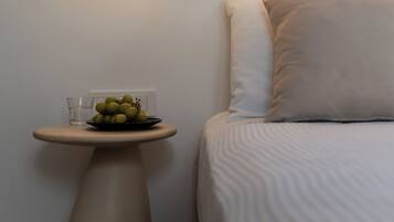 A modern bedroom with a bed, a round table with a plate of fruit, and a wall-mounted lamp.