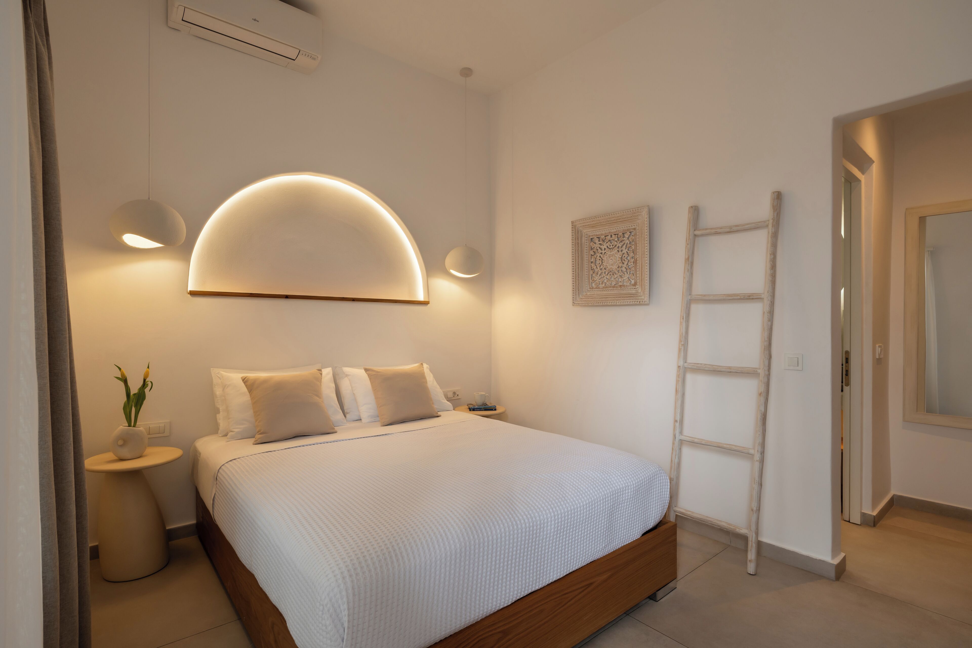 Une chambre à coucher avec un lit, des lampes de chevet, une applique murale, une échelle et un tableau encadré.