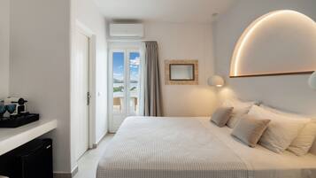 Una habitación de hotel moderna con una cama grande, una mesita de noche, un espejo y vistas al exterior.