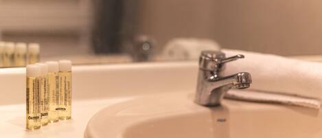 A bathroom sink with a mirror, a faucet, and a row of toiletries.