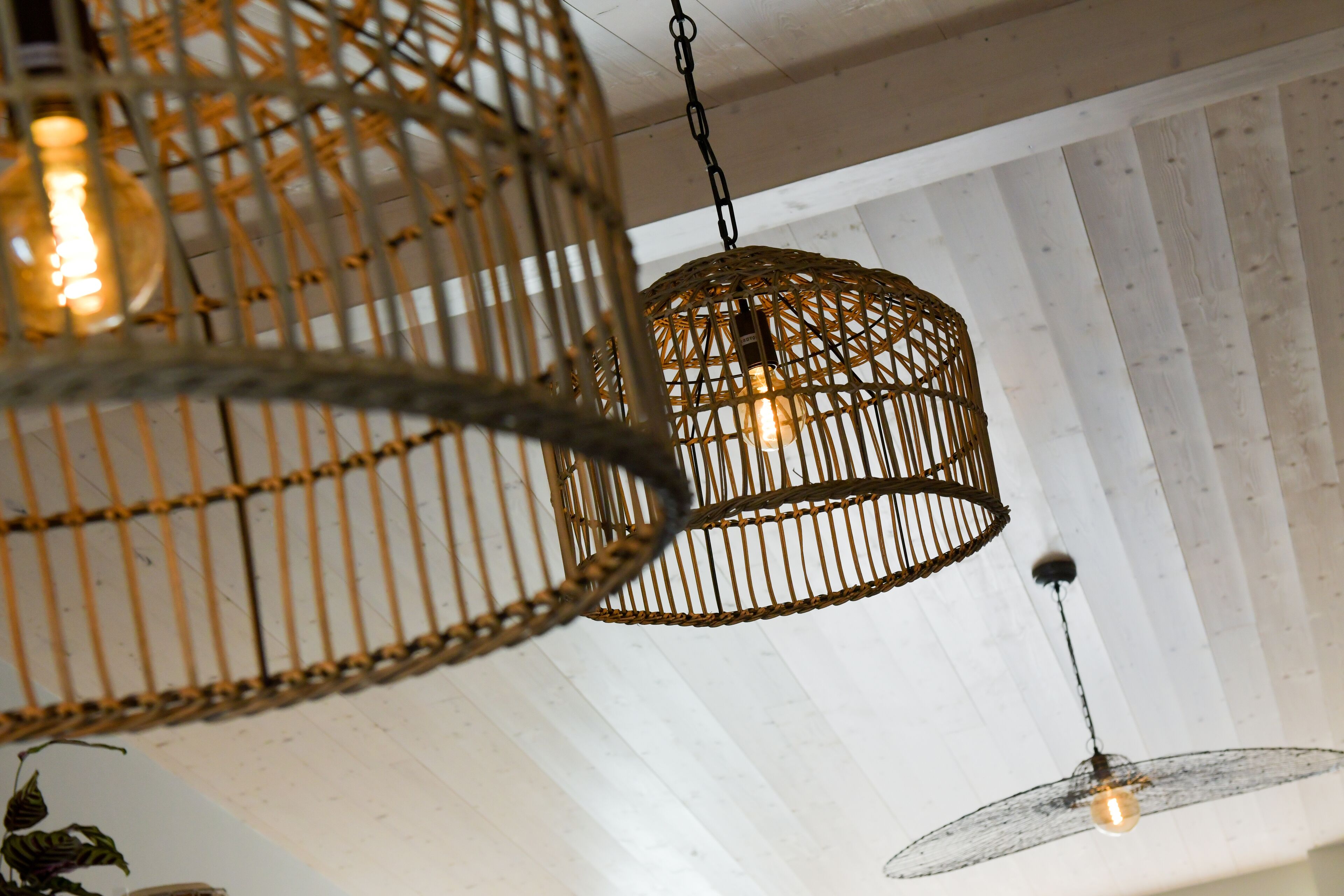A ceiling with woven metal light fixtures and a wooden panel design.