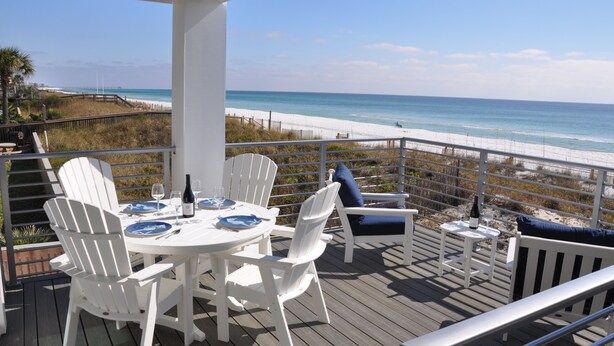 Eine Terrasse mit Tisch für zwei Personen mit Blick auf einen Strand.