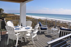 A deck with a table set for two, overlooking a beach.