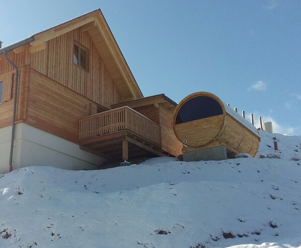 Una cabaña de madera con balcón y un ventanal cilíndrico grande.