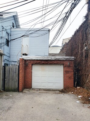 Adjacent to a brick wall, this garage features a white door and a wooden fence.