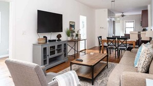 A living room with a flat-screen TV, grey cabinet, wooden coffee table, and beige sofa. - Urban Oasis - Walk to Restaurants, Transit & More! (Chicago)